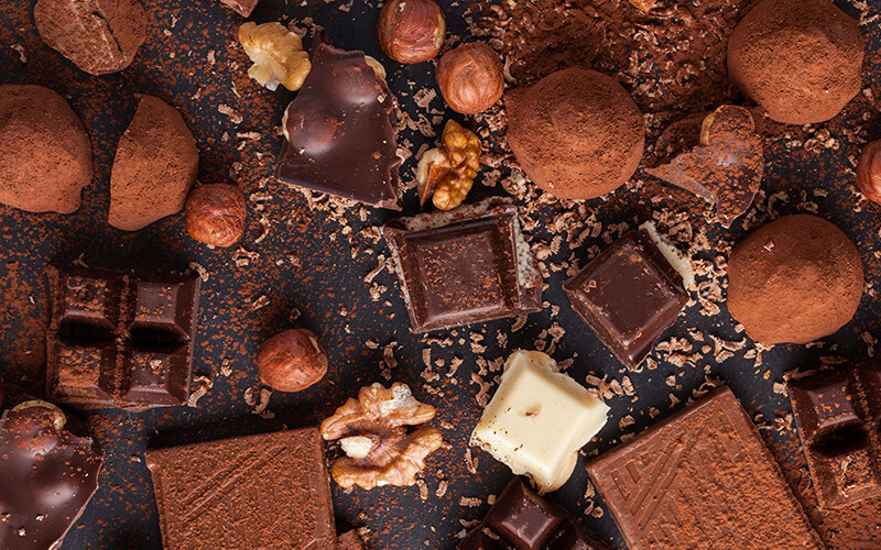 Leckere Schokolade und Gewürze auf schwarzem Hintergrund.