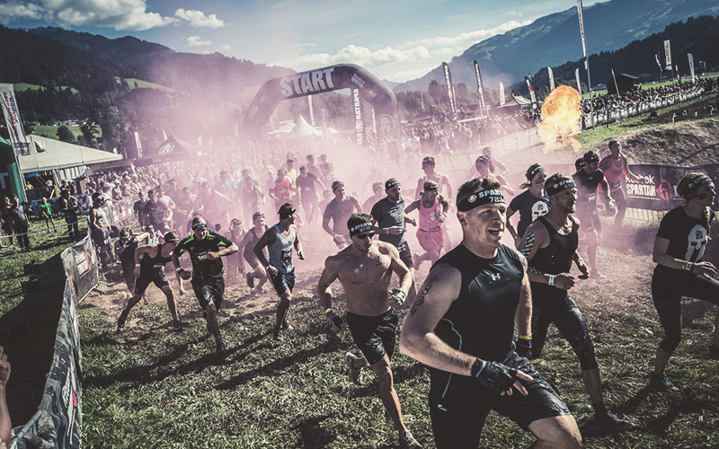 Starterfeld des Spartan Race Tirol direkt nach dem Start vor hügeliger Bergkulisse