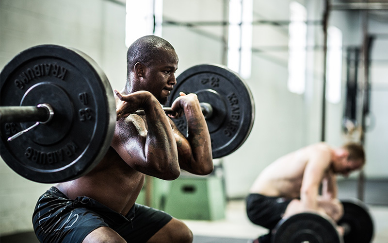 Due uomini si allenano con bilanciere in Crossfit Box