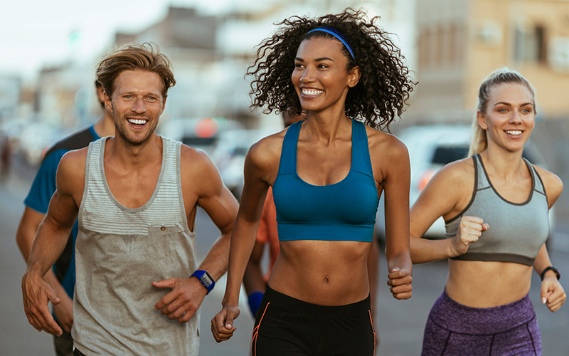 2 Frauen und 2 Männer joggen in der Gruppe durch die Stadt und motivieren sich gegenseitig