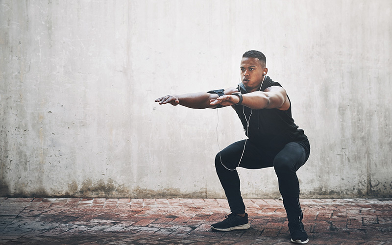 Air squat - Uomo esegue piegamenti sulle ginocchia senza pesi