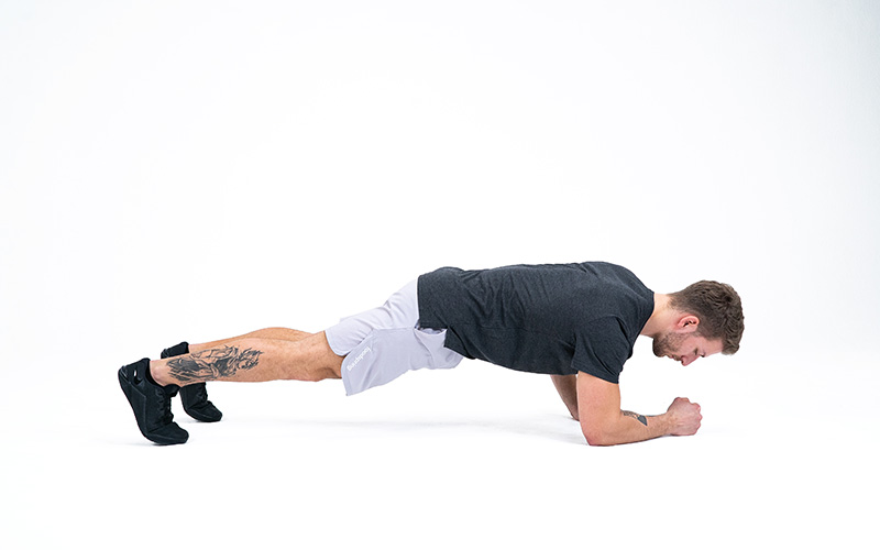 A white man demonstrates correct technique for a plank.