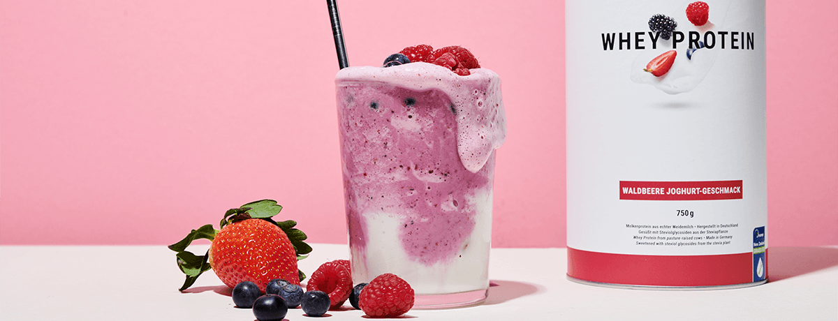 A canister and glass full of Whey Protein with a few fresh berries on the side. Whey Protein is a great tool post-strength training for women or men