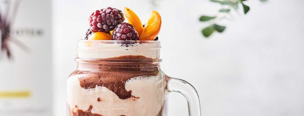 a vanilla chocolate shake in light and dark brown layers topped with fresh fruits and berries