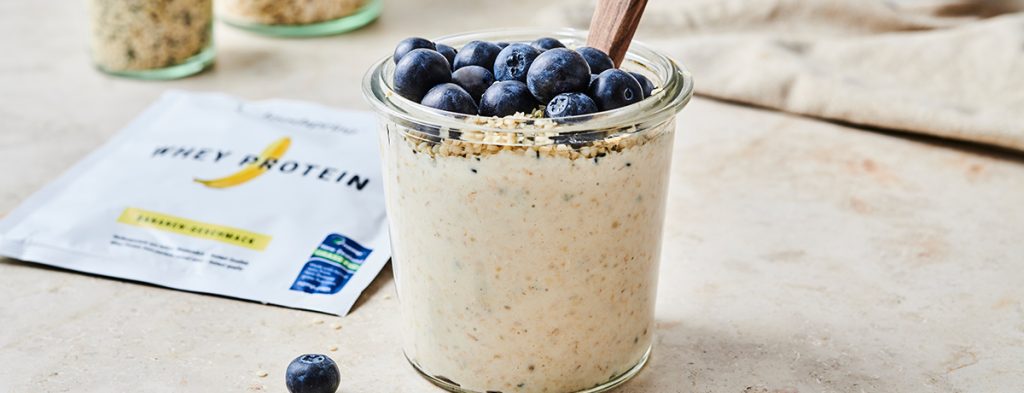 A glass jar of overnight oats topped with fresh blueberries