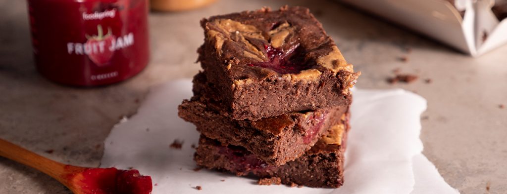 a stack of peanut butter and jelly brownies on a sheet of parchment paper.