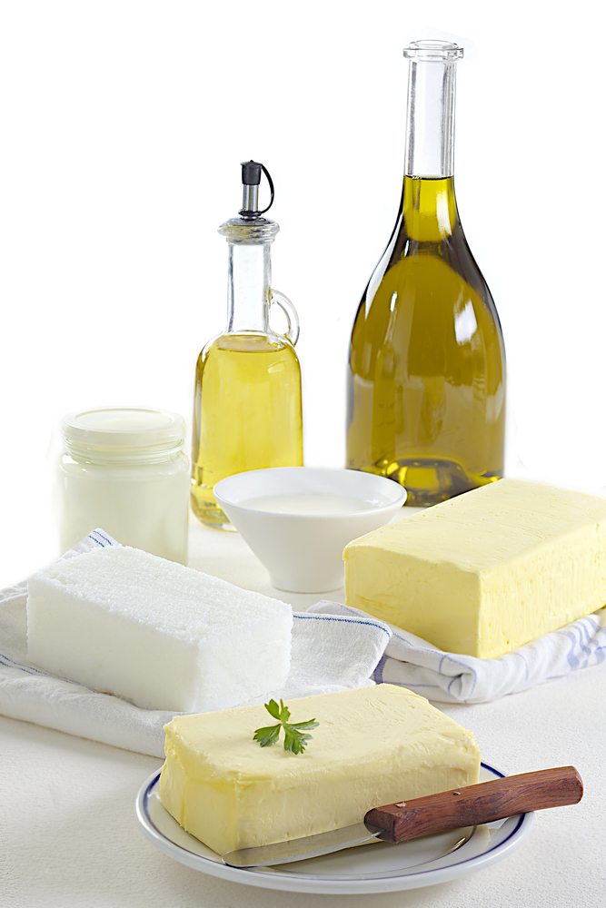 Eine Auswahl fettreicher Lebensmittel mit Butter, Öl, Käse und Milch.