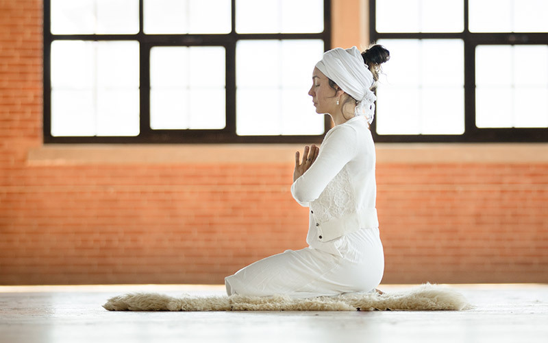 Frau praktiziert Kundalini Yoga
