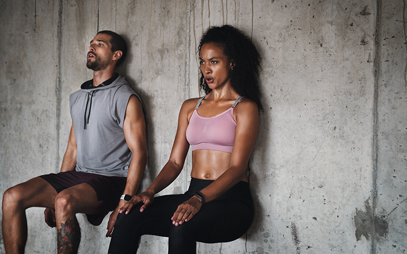 Ein Mann und eine Frau machen Wall Sits