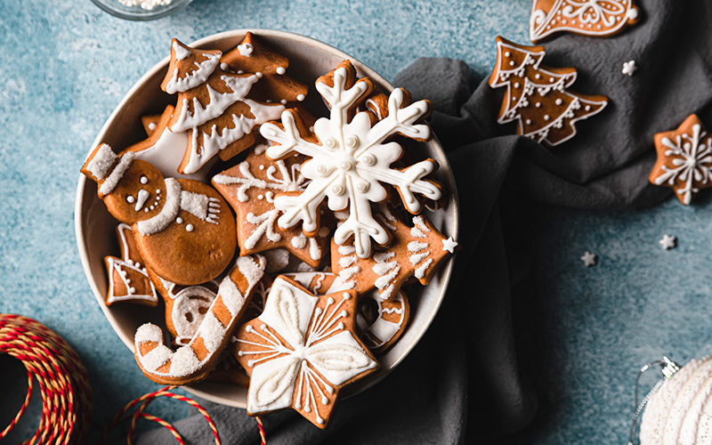 A bowl holds an assortment of healthy Christmas cookies decorated with white piped icing