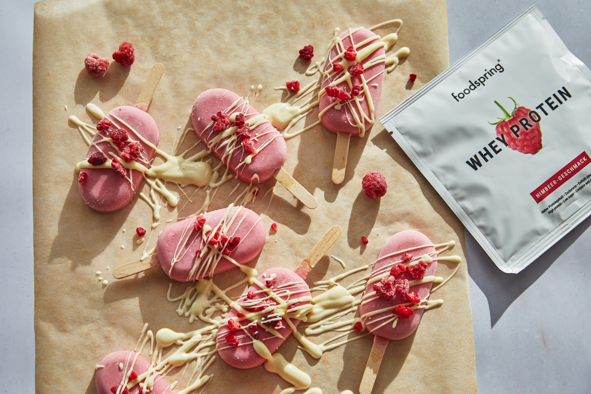 Raspberry Yogurt Popsicles Drizzled with White Chocolate on a Piece of Parchment