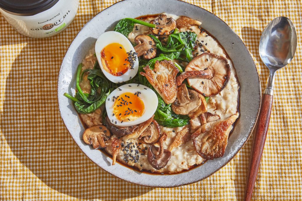 savoury oatmeal in a bowl topped with soft boiled egg, mushrooms and spinach