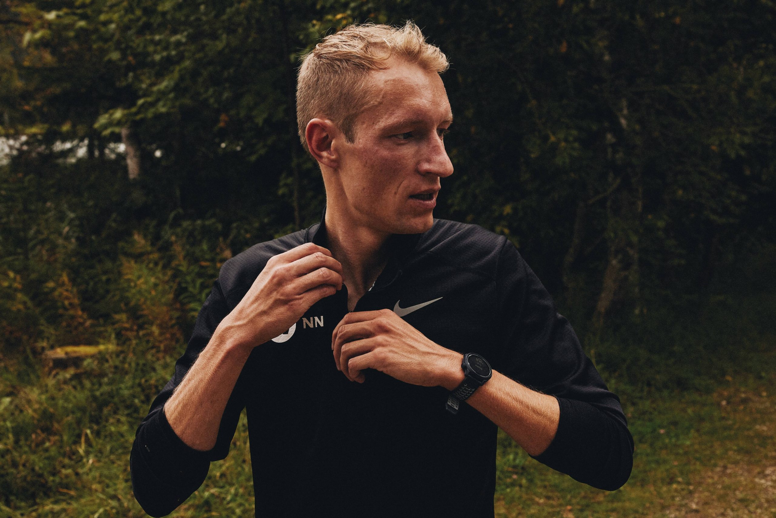 Björn Koreman, maratoneta, con indosso un top nero Nike, guarda lontano dall'obiettivo con un orologio sportivo al polso.